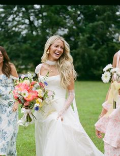 the bride is walking with her bridal party in the park, dressed in pastel florals