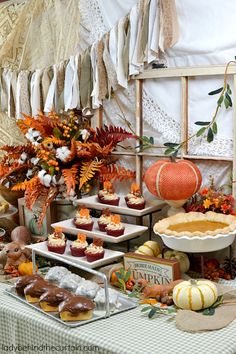 a table topped with lots of cupcakes next to a pie and other foods