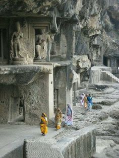 several women in sari are walking up the steps to an ancient building with statues on it