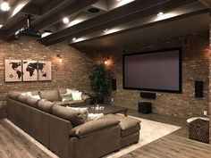 a living room filled with furniture and a flat screen tv mounted to the side of a brick wall