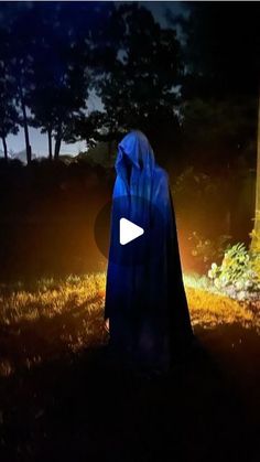 a person wearing a blue cloak standing in the dark