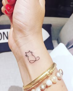 a woman's wrist with a cat tattoo on the left side of her arm