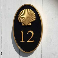 a black and gold sign with the number 12 on it's side is mounted to a white wall