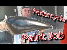 a man holding up a large black object with the words motorcycle paint job on it