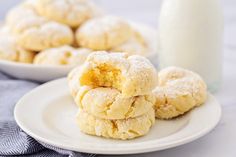 powdered sugar cookies on a white plate next to a glass of milk and a bottle of milk