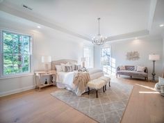 a large bedroom with white walls and wooden floors, along with a chandelier hanging from the ceiling