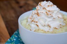 a white bowl filled with whipped cream on top of a blue and green table cloth