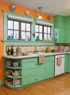 a kitchen with green cabinets and wooden floors in the center is decorated with colorful dishes