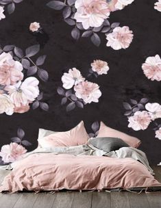 a bed sitting in front of a black wall with pink flowers on it