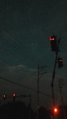 the traffic light is red at night on the street corner with power lines in the background