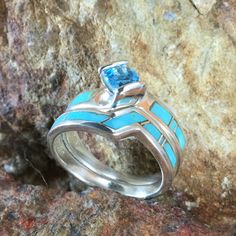 This beautiful Sterling Silver Ring Set, as part of the Arizona Blue Collection features Kingman Turquoise with a Blue Topaz. Engagement Ring Width: Top 5/8"; Shank 1/8" Band Width: 1/4"; Shank 1/8" The ring is designed by David Rosales, one of the finest contemporary Southwest Artists in the world. He is the founder and co-owner of Supersmiths, Inc. of Gallup, NM. Each ring is custom made and carries a lifetime guarantee. Fine Jewelry With Inlay For Anniversary, Blue Turquoise Ring With Gemstone Accents In Sterling Silver, Sterling Silver Turquoise Ring With Gemstone Accents, Turquoise Sapphire Gemstone Ring For Anniversary, Elegant Blue Turquoise Ring With Center Stone, Turquoise Sterling Silver Jewelry With Accent Stones, Turquoise Sapphire Ring With Accent Stones For Anniversary, Turquoise Sapphire Anniversary Ring With Accent Stones, Blue Multi-stone Aquamarine Jewelry