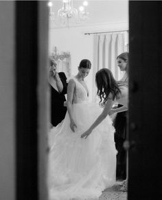 a woman in a wedding dress is helping another woman get ready for her big day