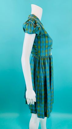 "A vintage 1940s cotton dress in a beautiful blue/green plaid print with a white pintuck detail on the bodice, button details, puff sleeves, a fitted waist and full skirt. Dress looks to be child sized but I wore it as a teenager and it closes with 4 buttons in the back. LABEL: - FABRIC: feels like cotton SHOULDERS: 13.5\" BUST: 36\" WAIST: 28\" max SHOULDER TO WAIST: 14\" HEM: 1.5\" of fabric under hem LENGTH: 35\" CONDITION: great, seam stress at underarms and waists, light pilling at underarm Fitted Blue Plaid Cotton Dress, Green Plaid Dress, Dress Puff Sleeve, Full Skirt Dress, Lace Caps, Vintage Clothing Online, Floral Print Maxi, House Dress, Skirt Dress