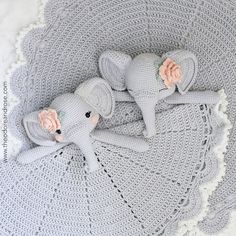 two crocheted stuffed elephants laying on top of a white doily with pink flowers