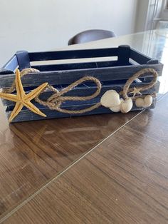 a wooden crate with starfish and seashells tied to it on a table