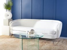 a white couch sitting next to a glass table