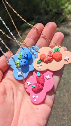 hand holding four different shaped necklaces in it's palm