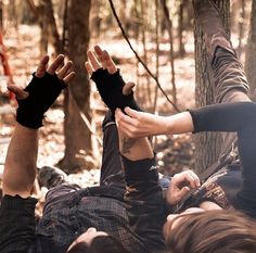 two people laying on the ground with their hands in the air