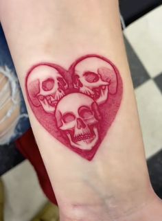 two skulls in the shape of a heart on a woman's arm with red ink