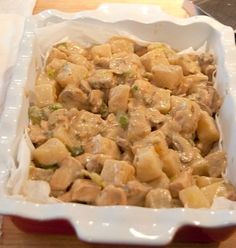 a casserole dish with meat and vegetables in it on a wooden counter top