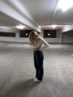 a blurry photo of a woman standing in an empty parking garage with her hands on her hips