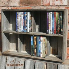 an old wooden shelf with several books on it and a brick wall in the background