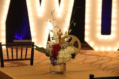 a vase filled with white and red flowers on top of a table next to a chair