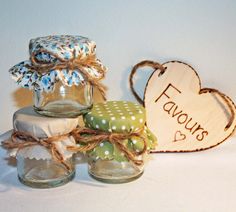 three jars are sitting next to each other with hearts on the top and two tags hanging from them