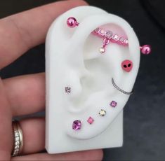 a person holding a fake ear with pink and white jewels on it's side