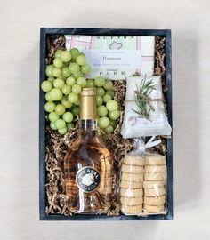 a bottle of wine, crackers and grapes in a box