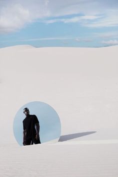 a man standing in the middle of a large white field with a blue circle behind him