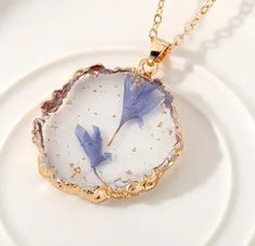 a white plate with a blue flower on it and a gold chain hanging from the front