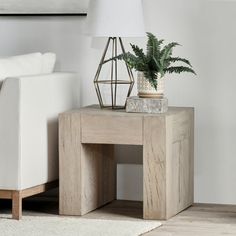 a white couch sitting next to a table with a potted plant on top of it