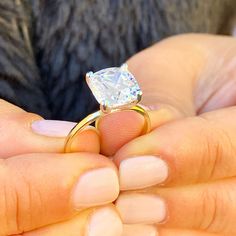 a close up of a person holding a ring with a diamond in it's middle