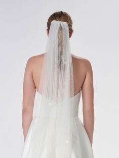 the back of a bride's wedding dress with a veil on her head and shoulders