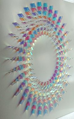 an abstract art piece made out of colored papers on a white surface with a circular hole in the middle