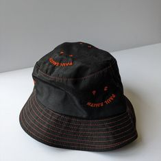 Paul Smith Black & Orange 'Happy' Bucket Hat. Great Condition - Never Worn. Size Small. Unisex. Cut From 100%, Breathable Cotton, This Black Bucket Hat Features A Repeated Ps 'Happy' Embroidered Pattern On The Front, In Orange. With Its Tonal Colouring, This Hat Is An Ideal Transitional Piece For The Changing Seasons. Black Bucket Hat For Spring, Black Cotton Hat, Casual Orange Bucket Hat With Short Brim, Trendy Orange Cotton Hat, Trendy Orange Adjustable Bucket Hat, Black Adjustable Short Brim Bucket Hat, Casual Adjustable Orange Bucket Hat, Adjustable Orange Cotton Bucket Hat, Orange Short Brim Hat, One Size