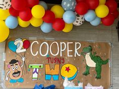 there is a sign that says cooper turns 1 and balloons in the air above it