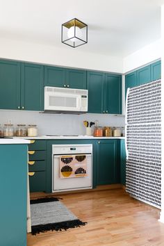 a kitchen with teal cabinets, white appliances and wooden floors is pictured in this image