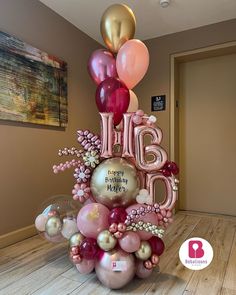 a birthday cake made out of balloons with the words happy birthday written on it in pink and gold