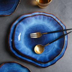 blue plates with gold forks and spoons on them