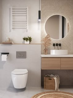 a white toilet sitting next to a bathroom sink under a round mirror on a wall