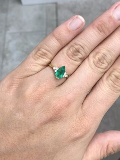 This ring features a 1.06-carat natural Colombian emerald, pear cut from the famous Muzo mines. Set in a secure two-prong setting, this extraordinary emerald has a stunning green color and very good eye clarity, Minor imperfections are normal for genuine Colombian emeralds. Three brilliant round diamonds accent the emerald on either side. Excellent colorless diamonds with VS clarity highlight the pear cut emerald. Set in silky 18K yellow gold. Perfect for everyday wear. Metal Purity: 18K Yellow Gia Certified Green Pear-shaped Diamond Ring, Pear-shaped Brilliant Cut Emerald Ring, Green Pear-shaped Diamond Ring, Gia Certified Pear-shaped Emerald Ring, Gia Certified Green Pear-shaped Rings, Fine Jewelry Emerald Ring With Brilliant Pear-shaped Cut, Teardrop Emerald Ring With Brilliant Cut, Teardrop Emerald Ring With Prong Setting, Green Teardrop Emerald Ring With Brilliant Cut