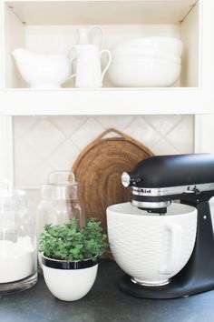 a kitchen counter topped with a mixer next to a potted plant