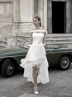 a woman in a white dress standing next to a car