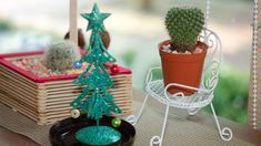 a small christmas tree sitting on top of a wooden table next to a potted cactus