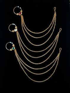 four different types of necklaces and ear rings on a black velvet surface with gold chains