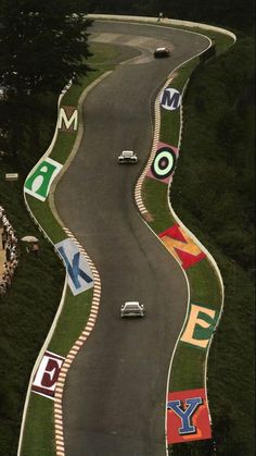 an aerial view of a race track with cars driving on the road and flags painted all over it