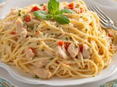 a white plate topped with pasta covered in chicken and tomato sauce next to a fork