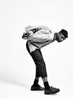 a young man is leaning on his skateboard and posing for a black and white photo